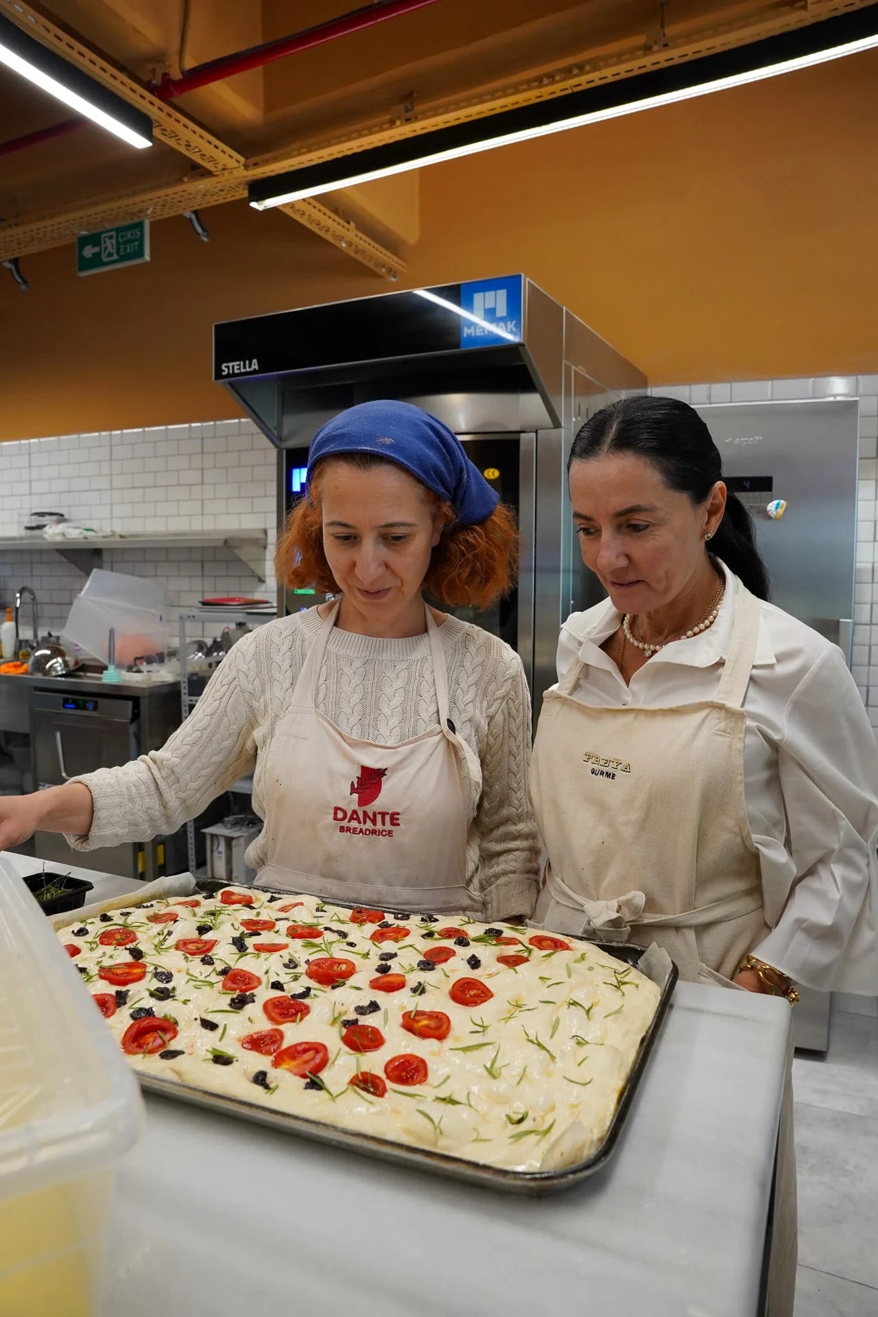 Dante ve Freya önlükleriyle iki kişi mutfakta focaccia hazırlarken